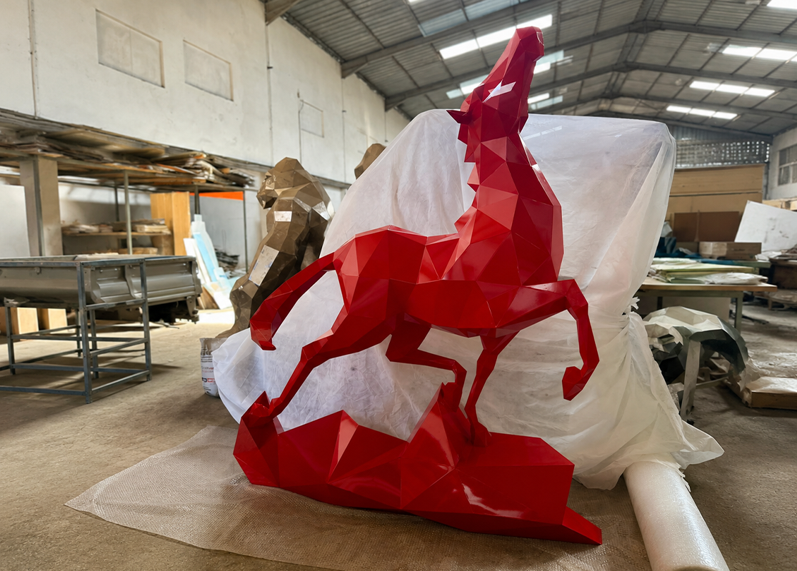 Large red faceted rearing horse sculpture with glossy lacquer finish during production in the JOJMA sculpture workshop in Morocco